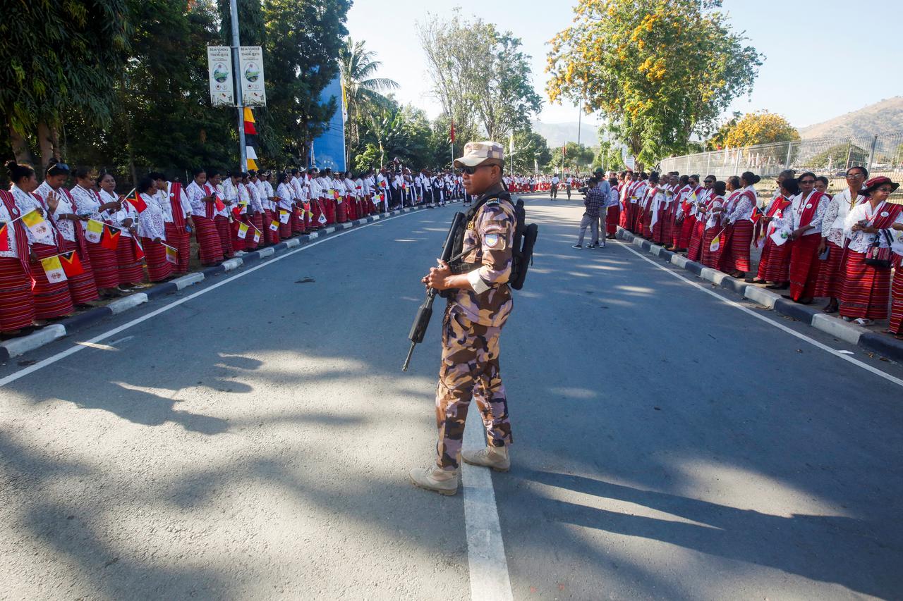 An armed soldier guards as people wait for Pope Francis to arrive, before his departure to Singapore, in Dili