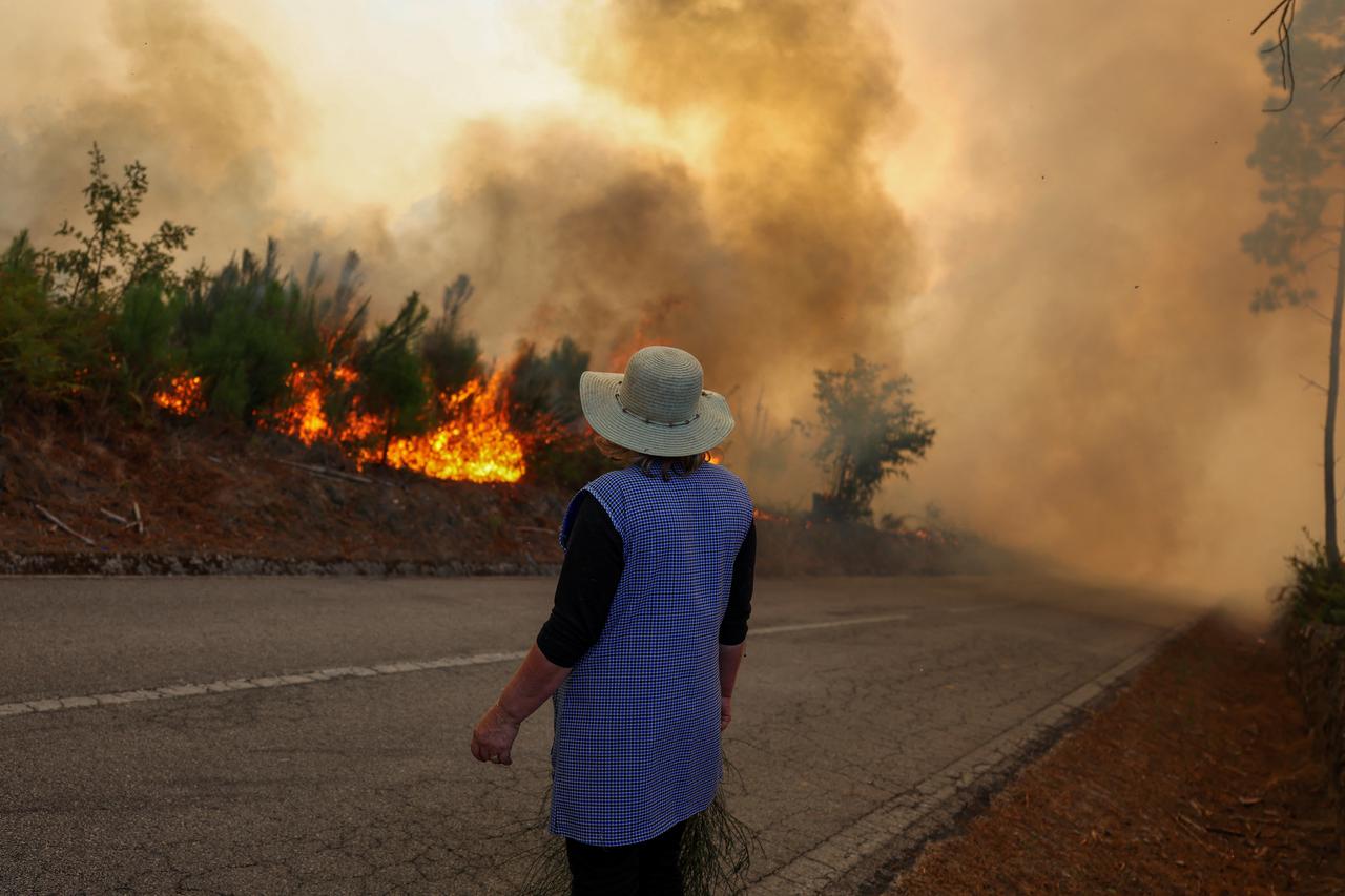 A woman stares at a wildfire in Penalva do Castelo