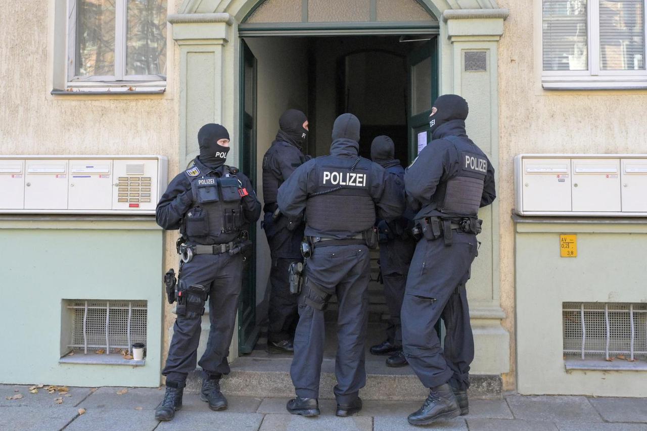 Masked German police officers guard a house in Dresden