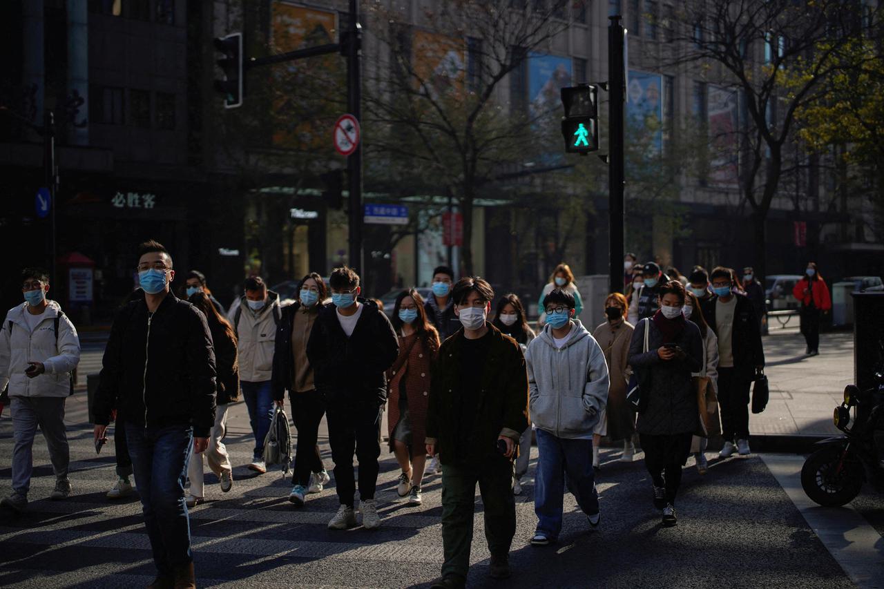 FILE PHOTO: People wearing protective masks walk on a street, following new cases of the coronavirus disease (COVID-19), in Shanghai