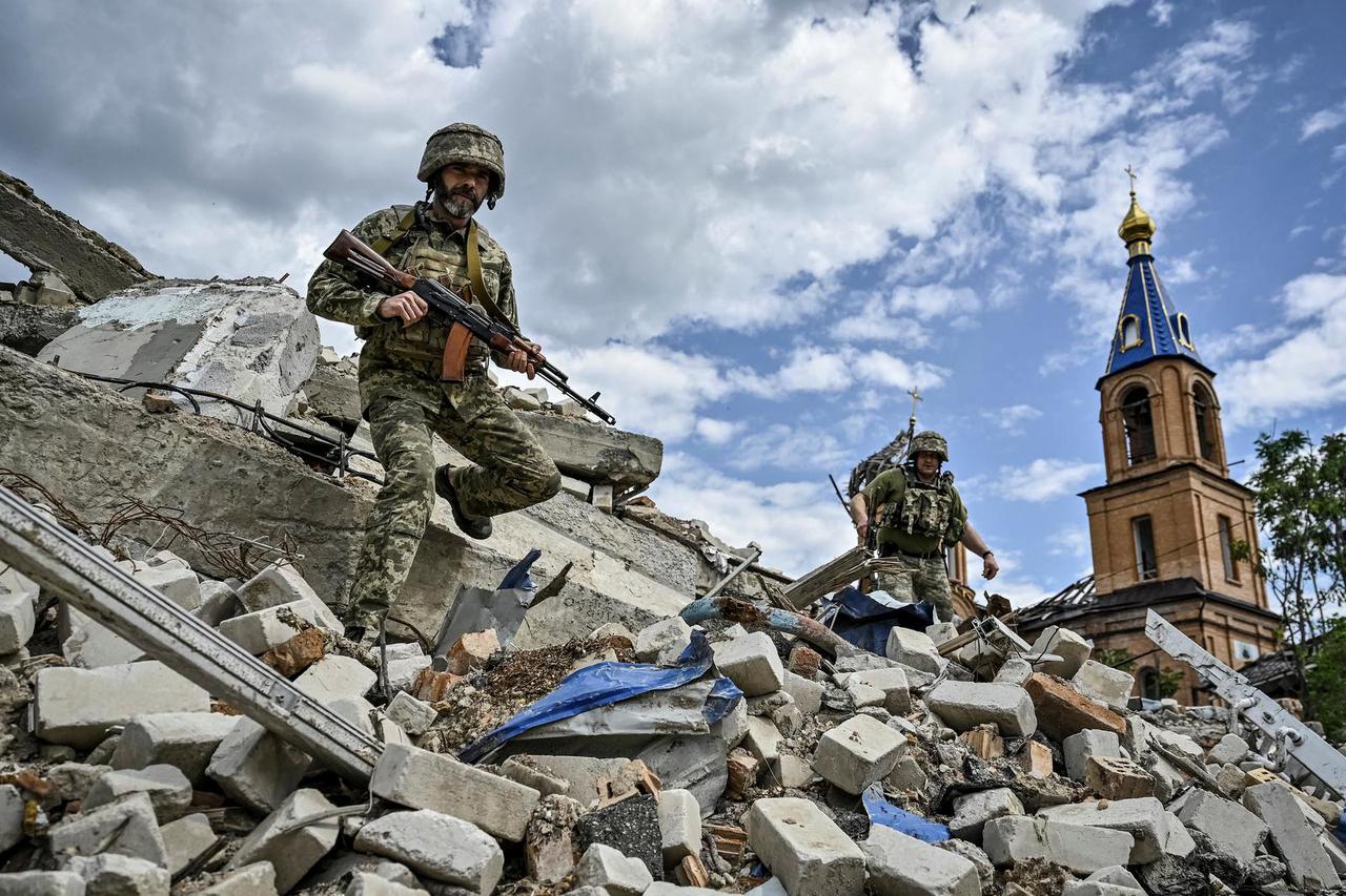 Ukrainian servicemen patrol an area heavily damaged by Russian military strikes in the town of Orikhiv