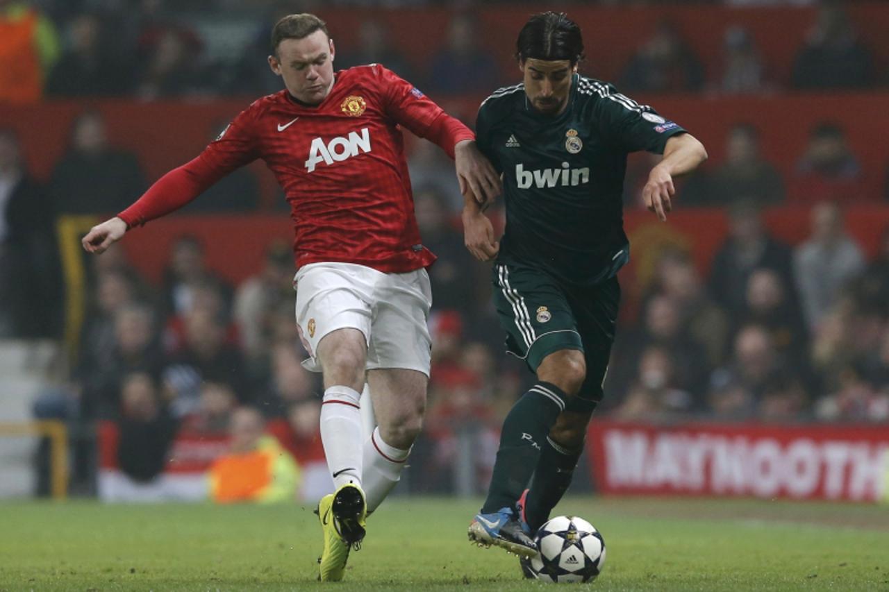 'Manchester United\'s Wayne Rooney (L) challenges Real Madrid\'s Sami Khedira during their Champions League soccer match at Old Trafford stadium in Manchester March 5, 2013.    REUTERS/Phil Noble (BRI